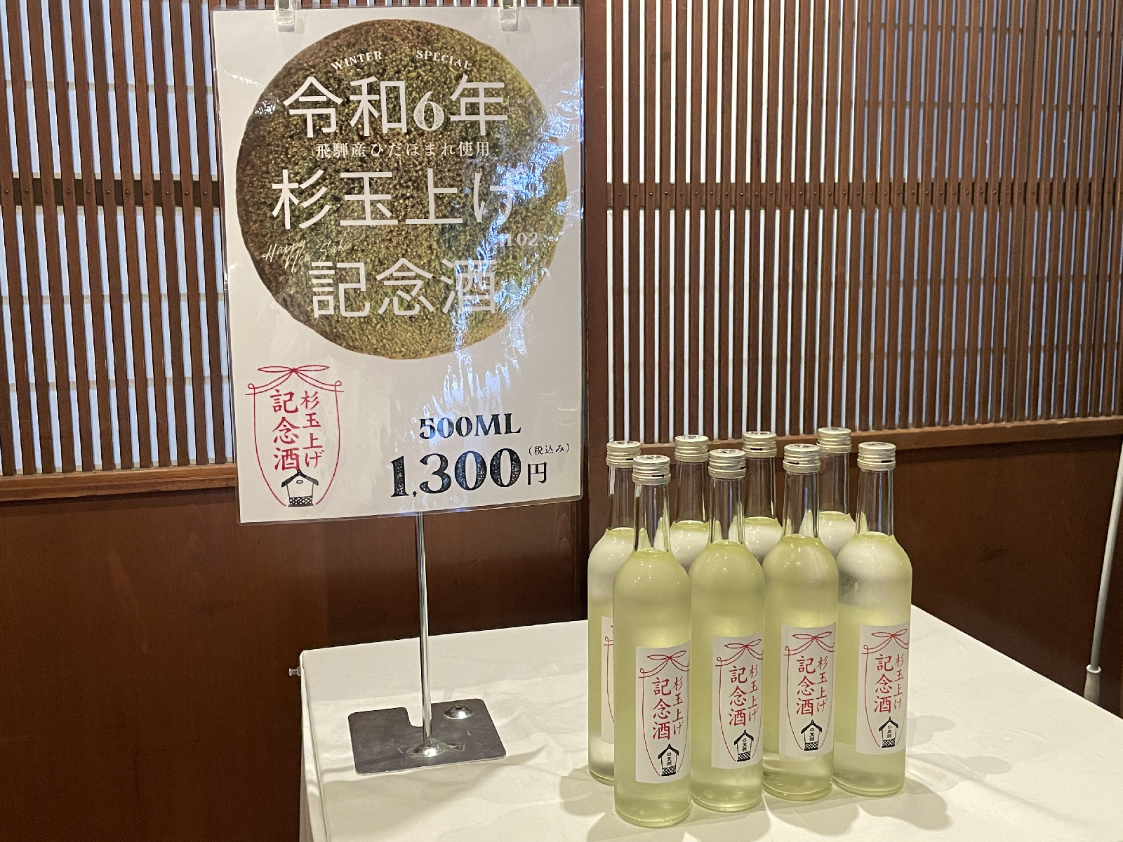 テーブルに整列した日本酒の瓶と説明するPOP