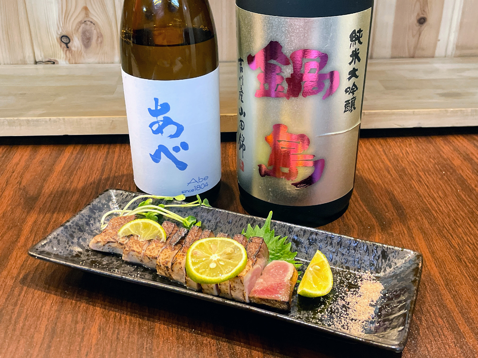 日本酒の瓶2本と惣菜のお皿