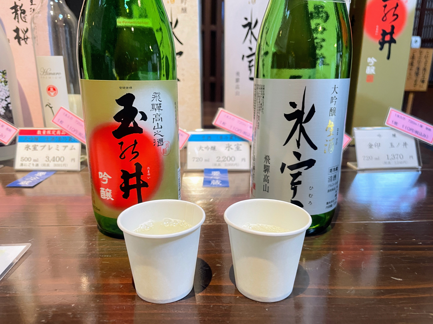 日本酒の瓶2本とお酒が入った紙コップ2個