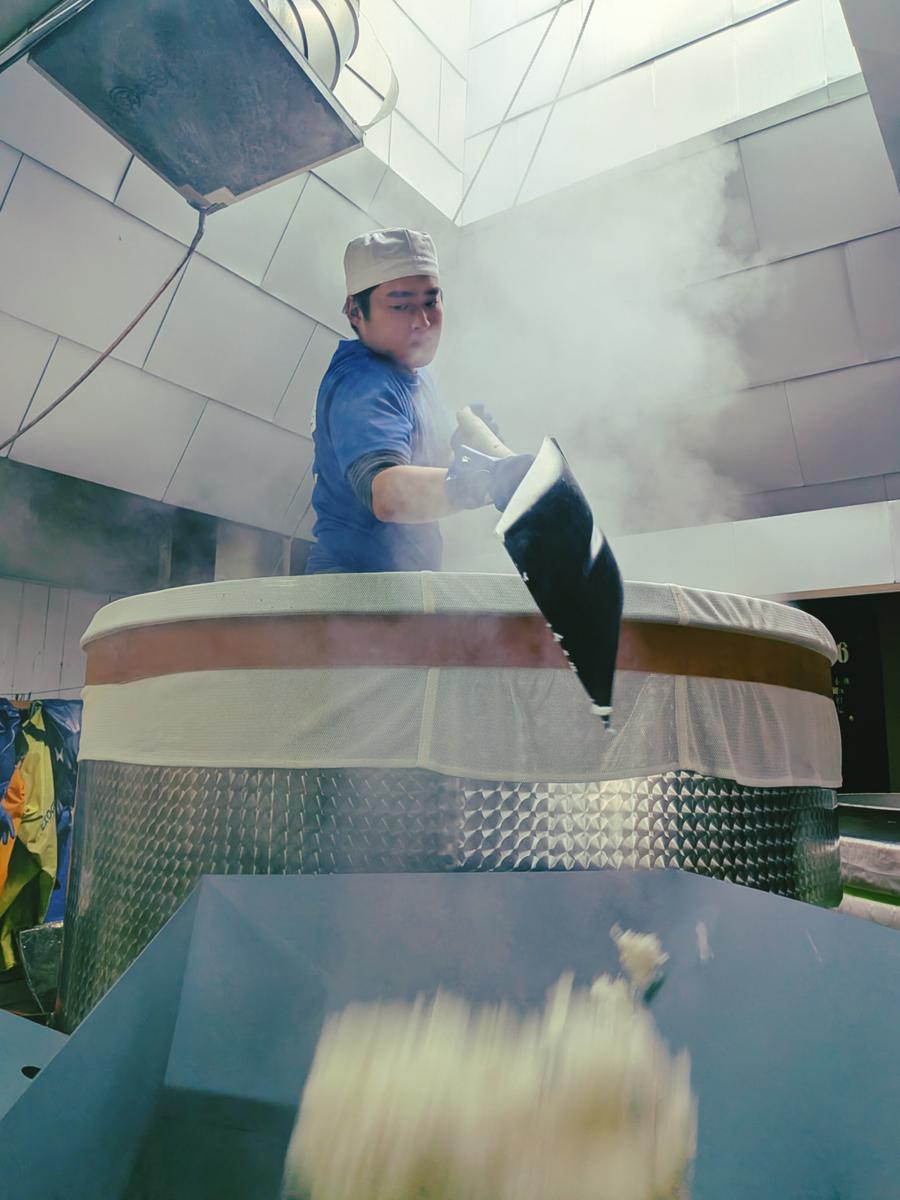 蒸上がった米を掘り、放冷機に移動する蔵人