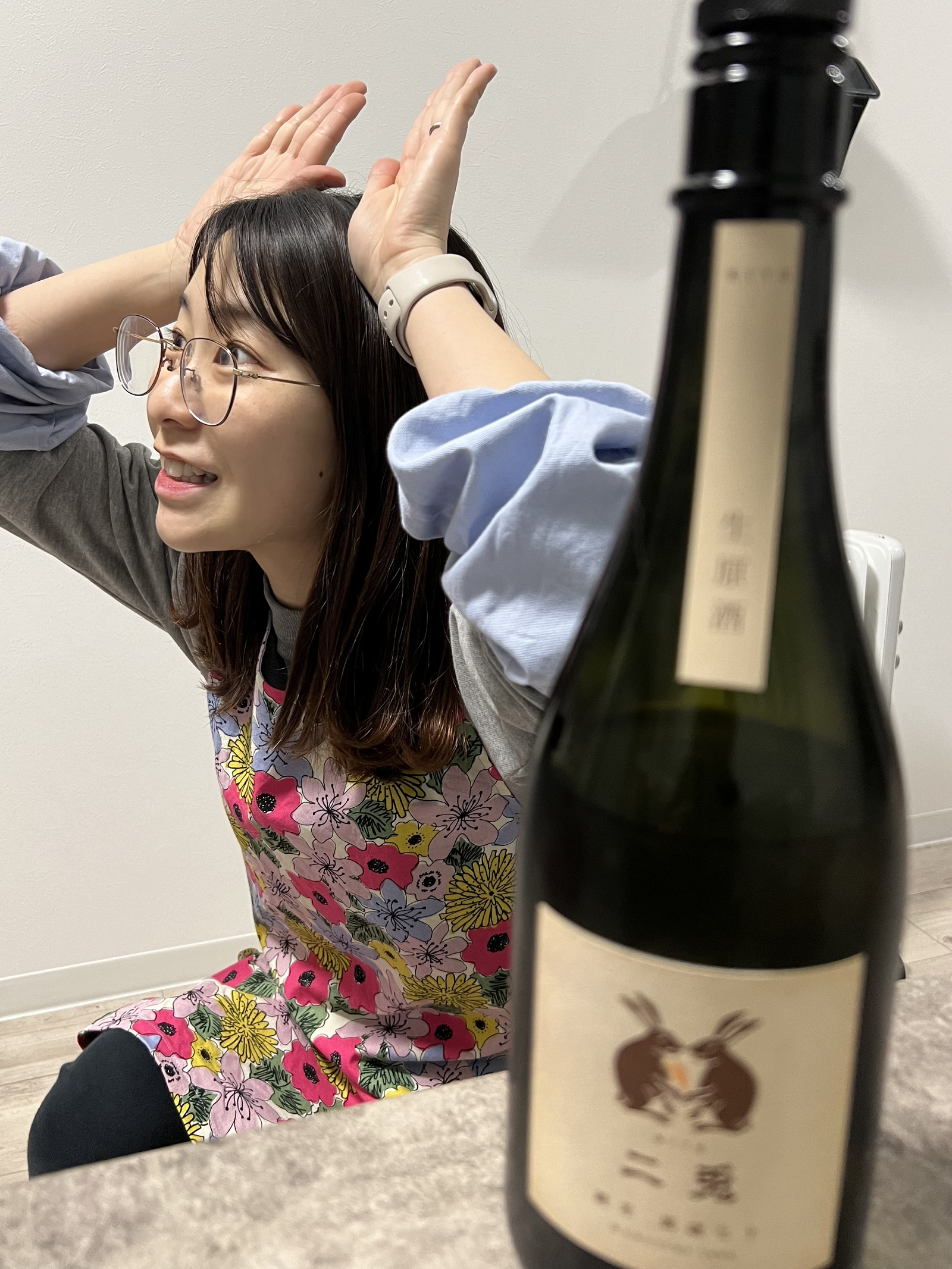 日本酒の瓶とうさぎのポーズをする女性