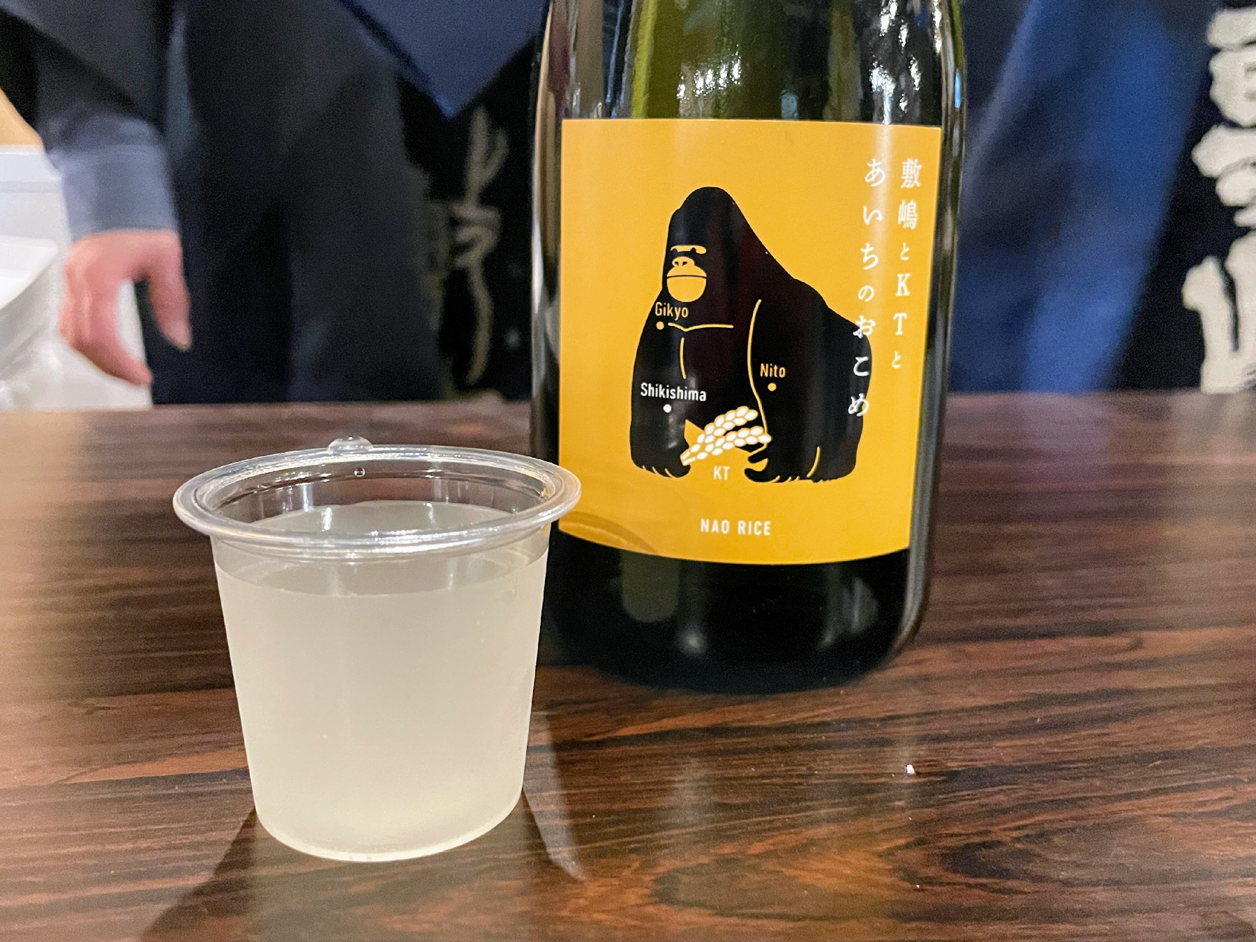 黄色のラベルの日本酒とプラスチックカップに入った日本酒