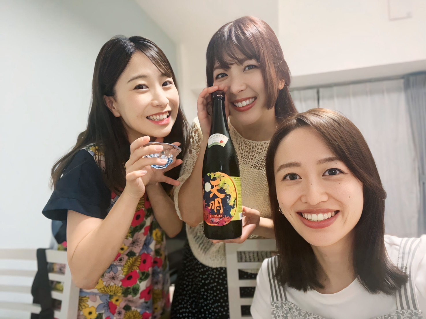 日本酒を持って笑顔を見せる女性3人