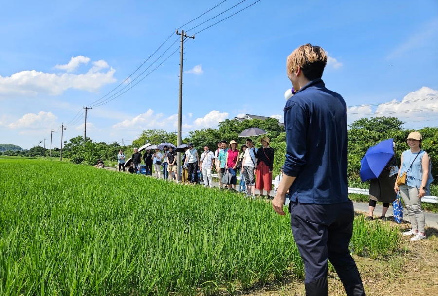 田んぼの前で拡声器を使って話す男性