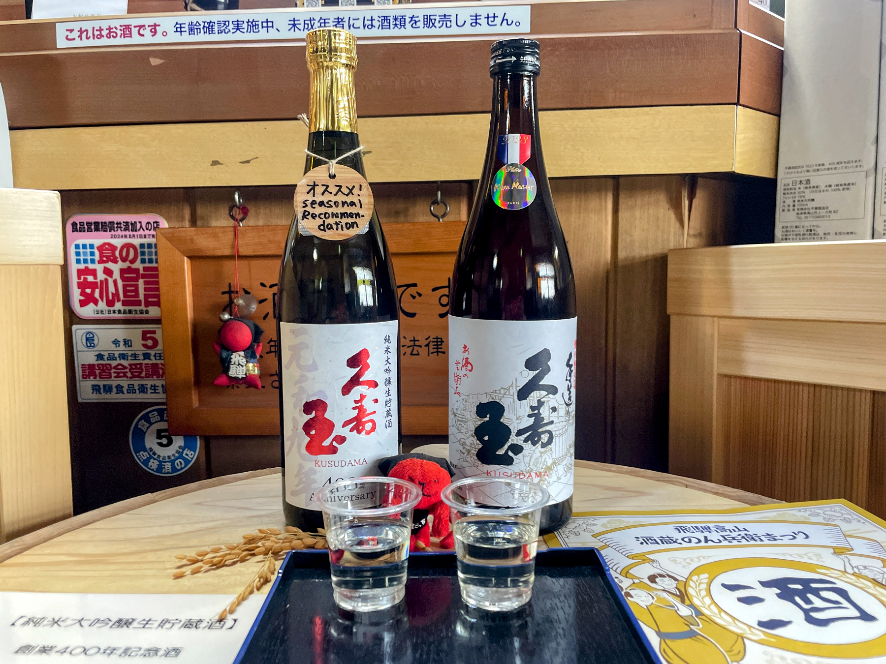 日本酒の瓶2本とお酒の入ったプラスチックカップ2個