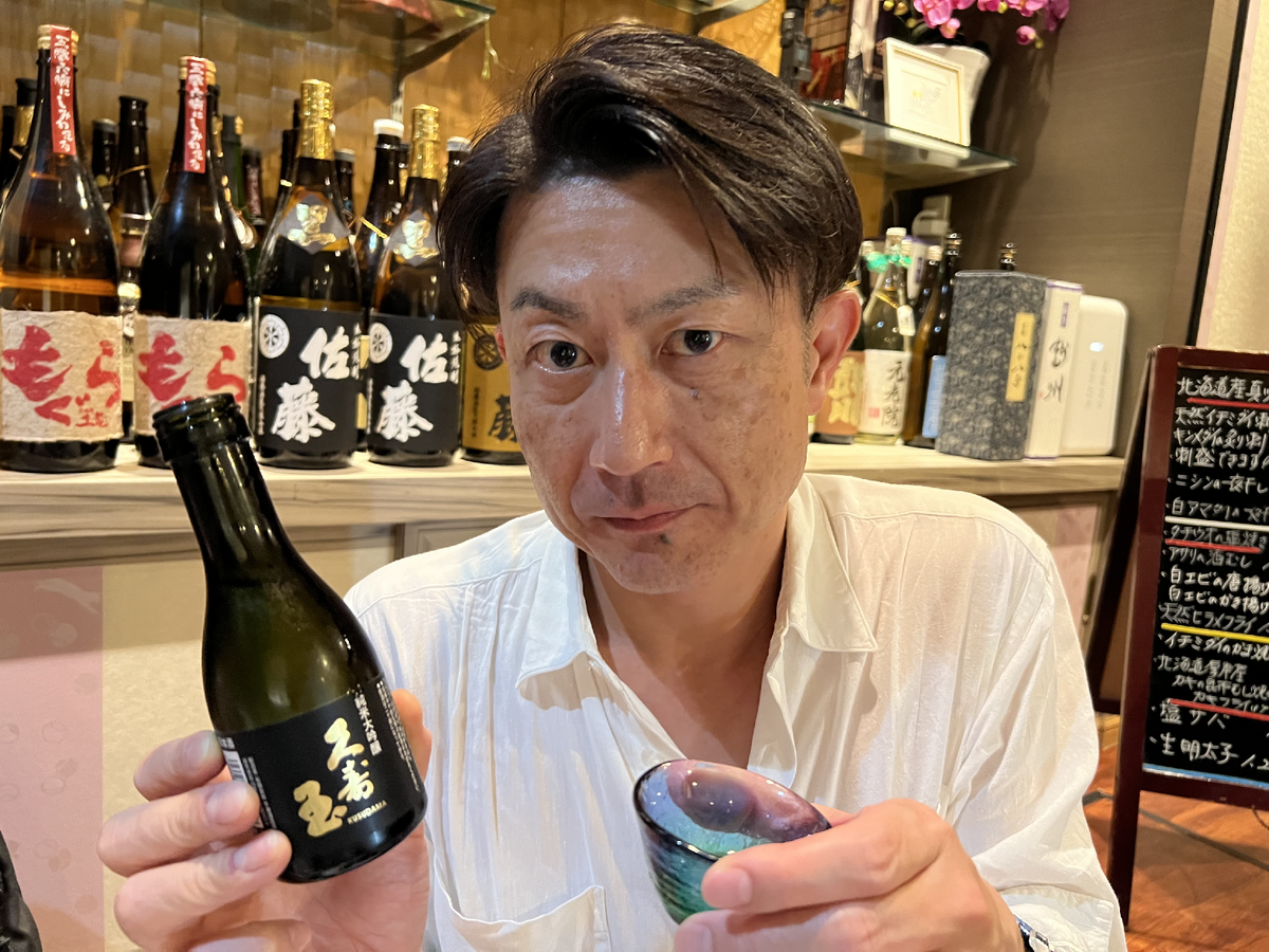 日本酒の瓶とお猪口を持つ男性