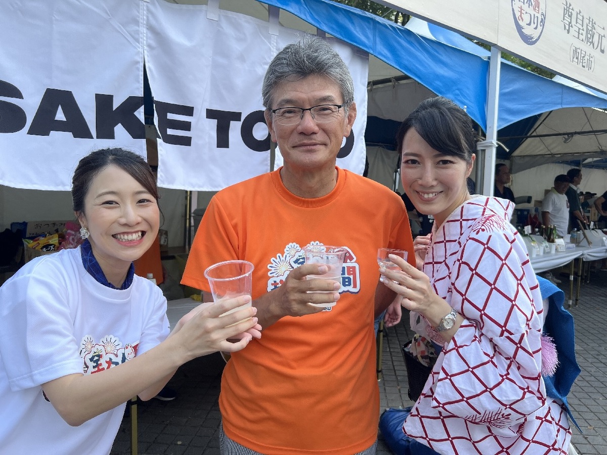 日本酒を手にする藤井社長と浴衣姿の女性と長江アナウンサー