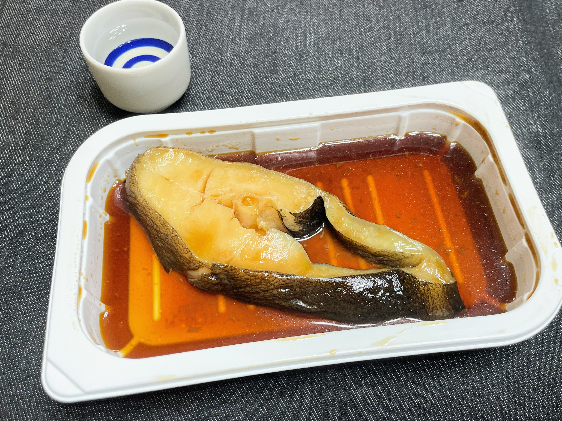 トレーに入った魚の煮つけとお猪口