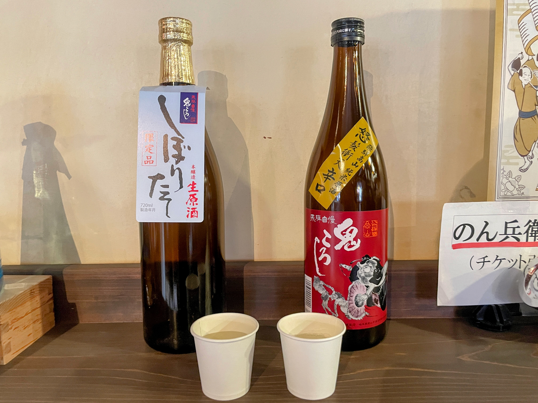 日本酒の瓶2本とお酒が入った紙コップ2個