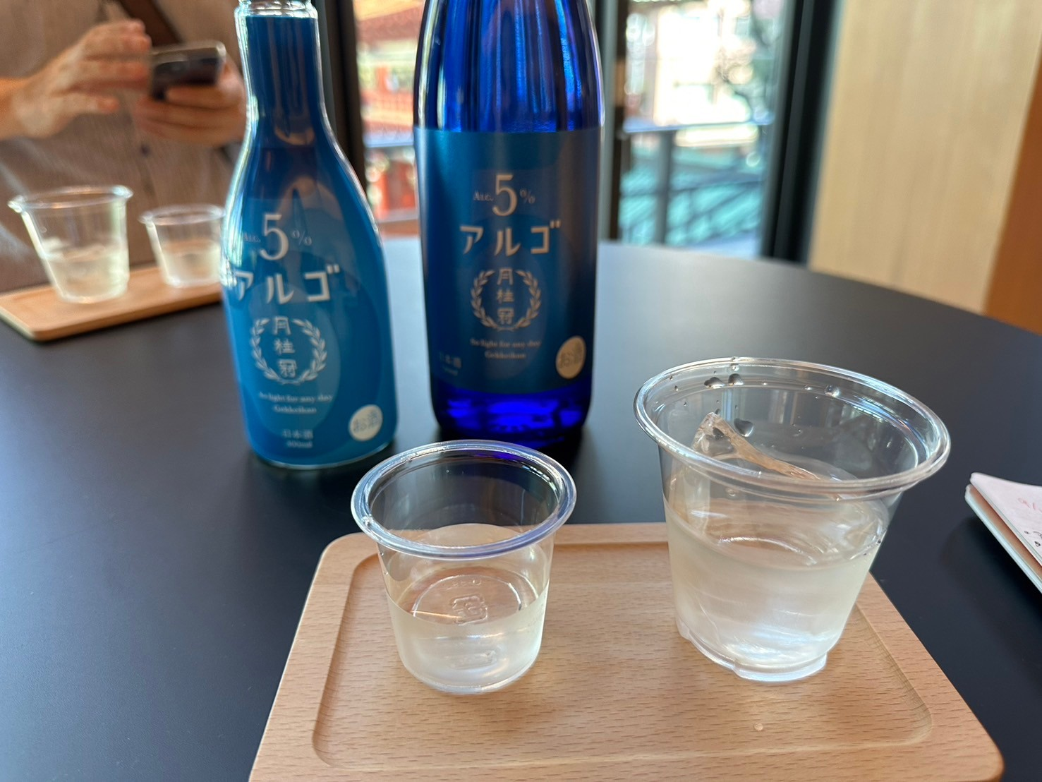 青色の日本酒の瓶とプラスチックカップに入った日本酒