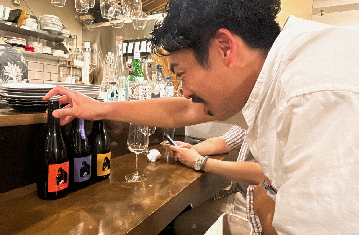 日本酒の瓶を眺める人