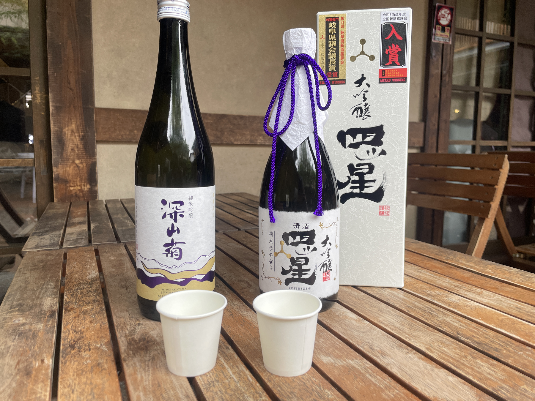 日本酒の瓶2本とお酒が入った紙コップ2個