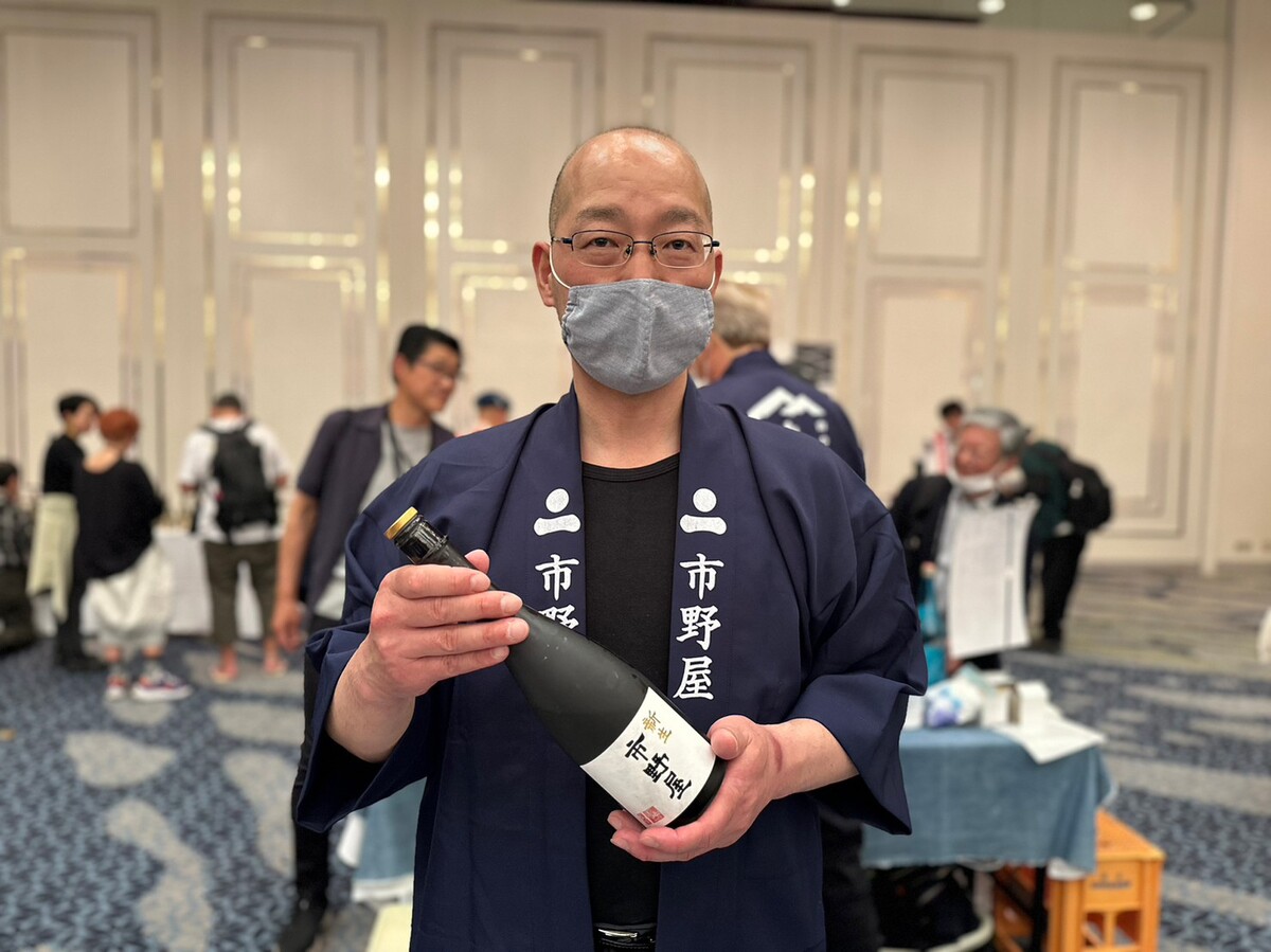 日本酒を持つ男性、マスクをしている