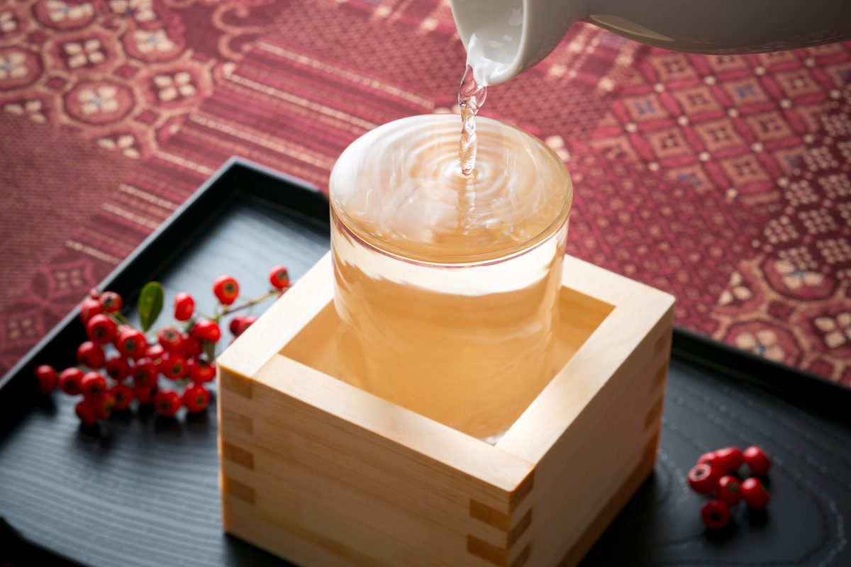 升の中に入ったグラスに日本酒を注ぐ様子