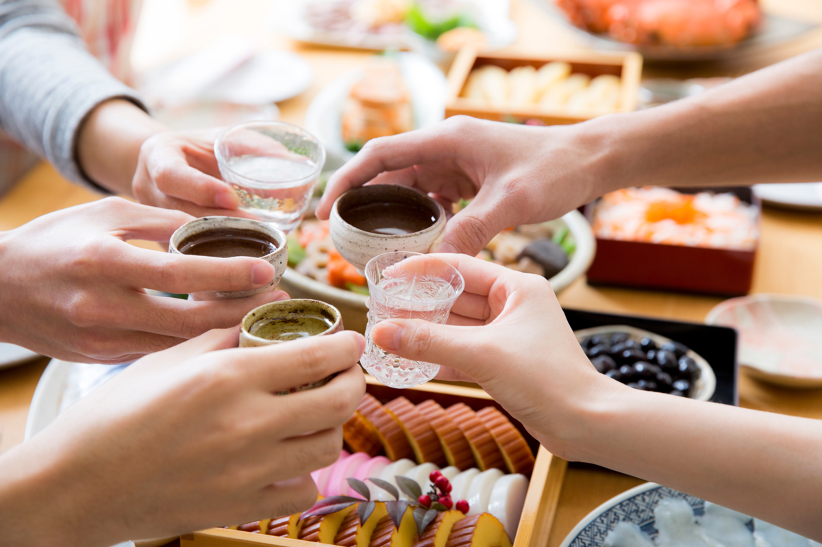 さまざまな酒器に入った日本酒で乾杯する手元