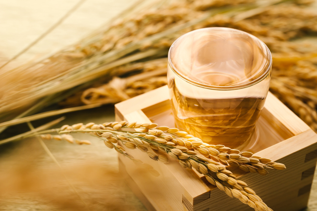 稲と升の中に入ったグラスに日本酒を注ぐ様子