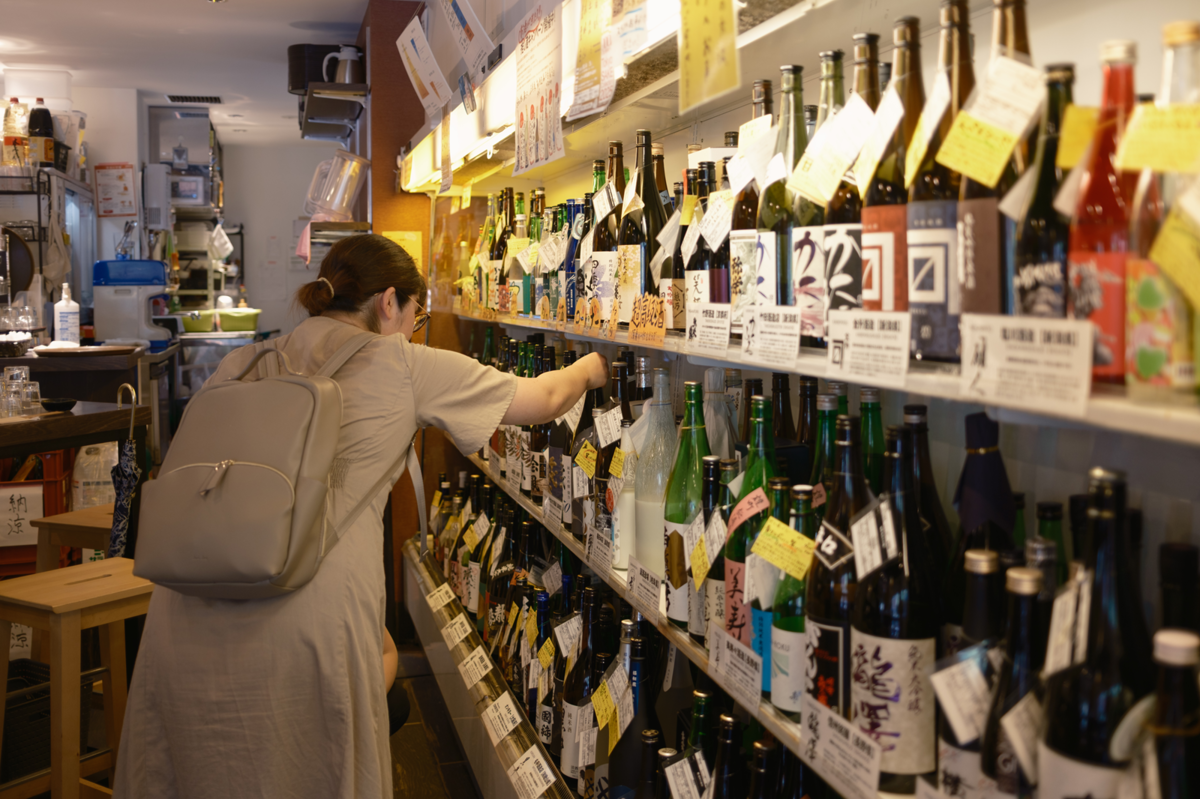 名酒センターで日本酒を選ぶ女性