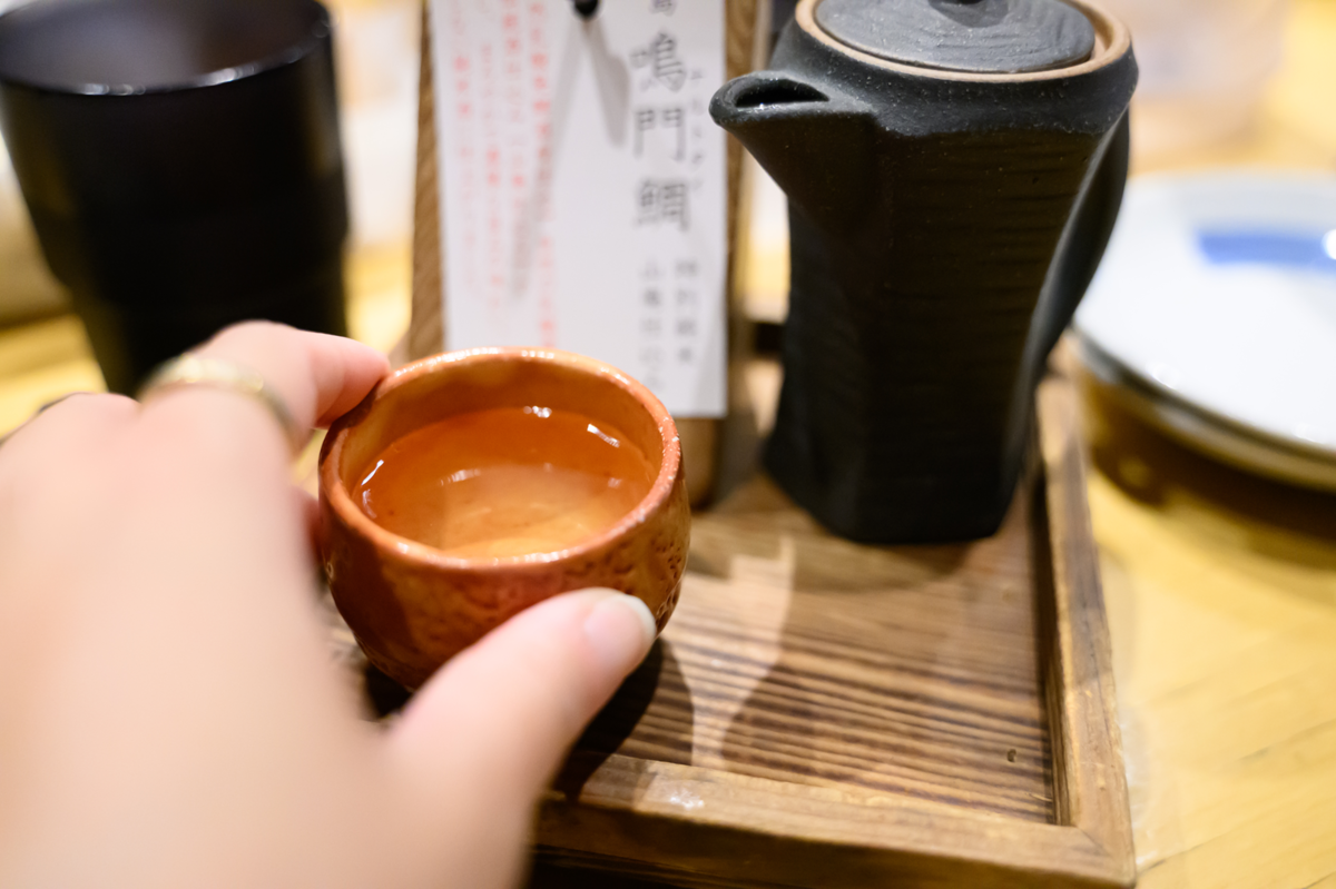 日本酒が入ったおちょこを掴む手元