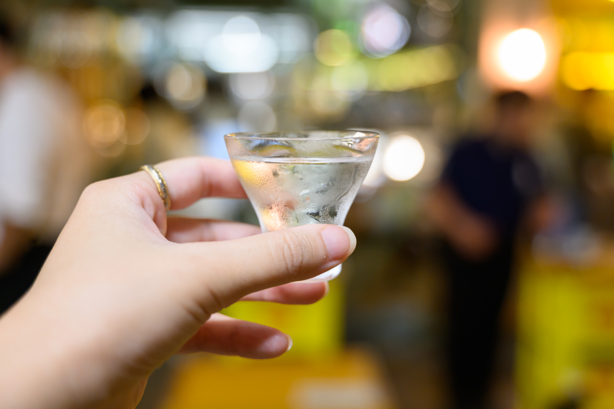 日本酒が入ったおちょこを持つ手元