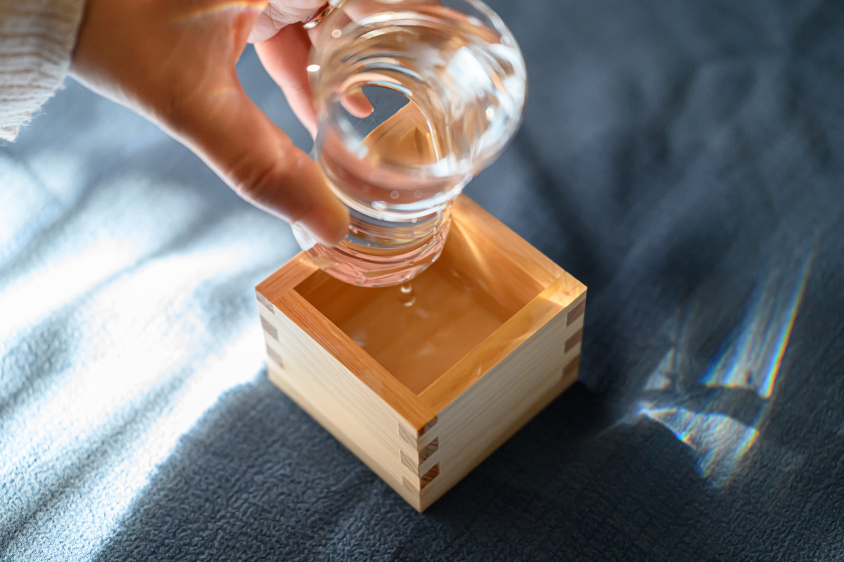グラスを傾けて日本酒を枡に移す様子