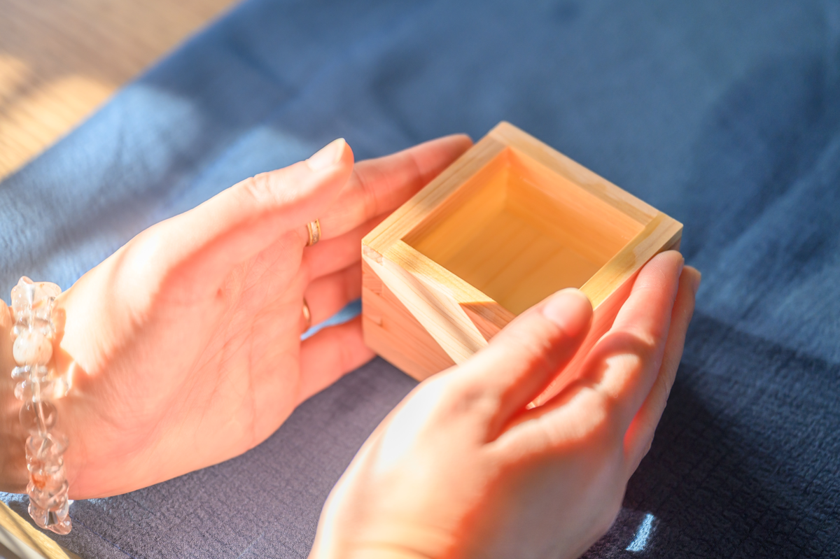 両手で枡を持ち上げる手元