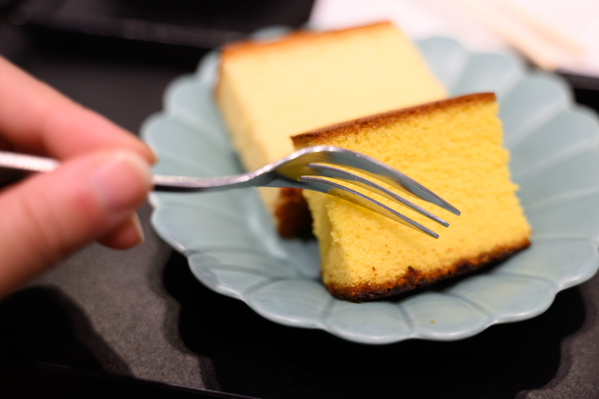 カステラにフォークを入れる手元