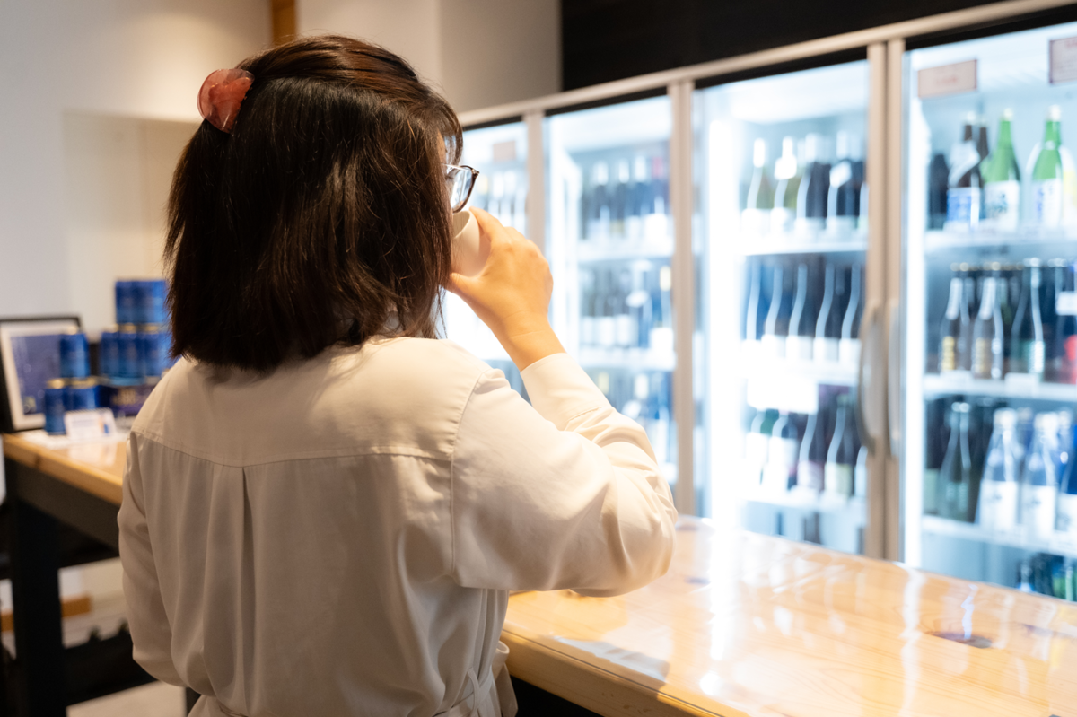 アンテナショップで日本酒飲み比べをする女性