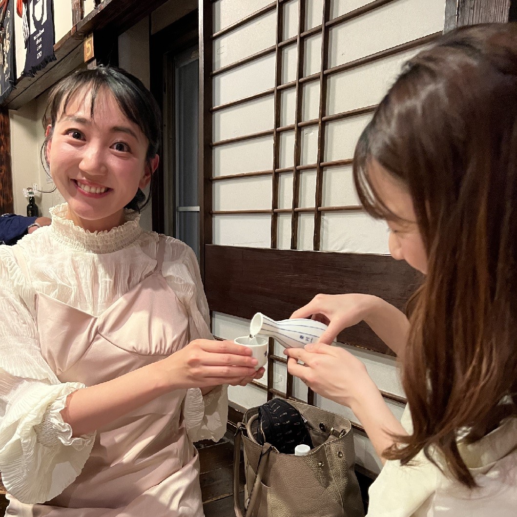 日本酒をお酌する長江麻美と小野アナウンサー