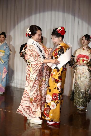 2024 Miss SAKE 愛知大会のグランプリの女性が、2025年グランプリの女性にたすきをかける様子