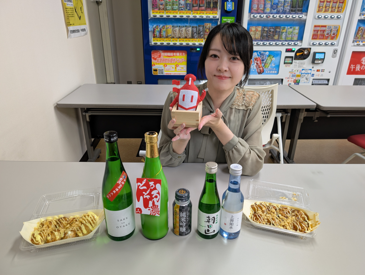 たこ焼きと日本酒とお酒くんを持つ女性