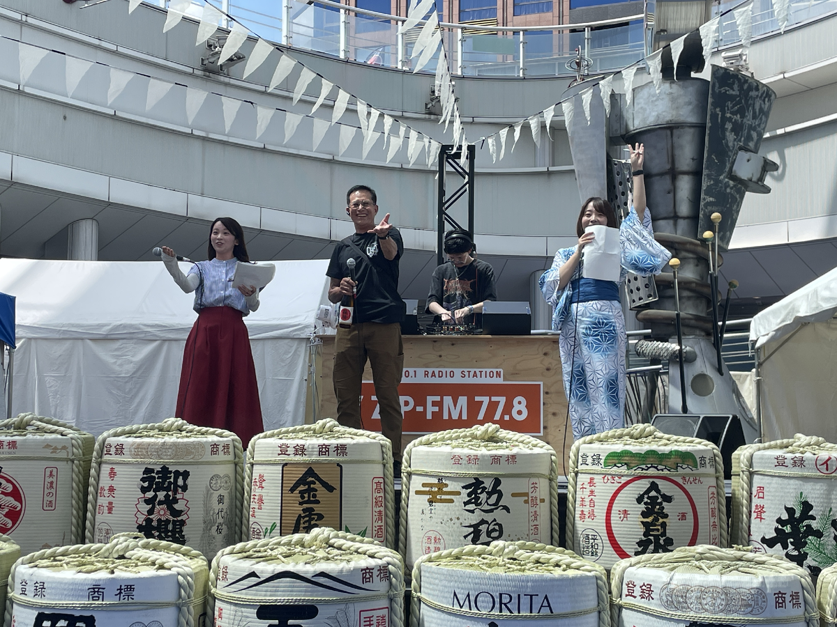 酒樽が並んだステージに立つ男性と女性