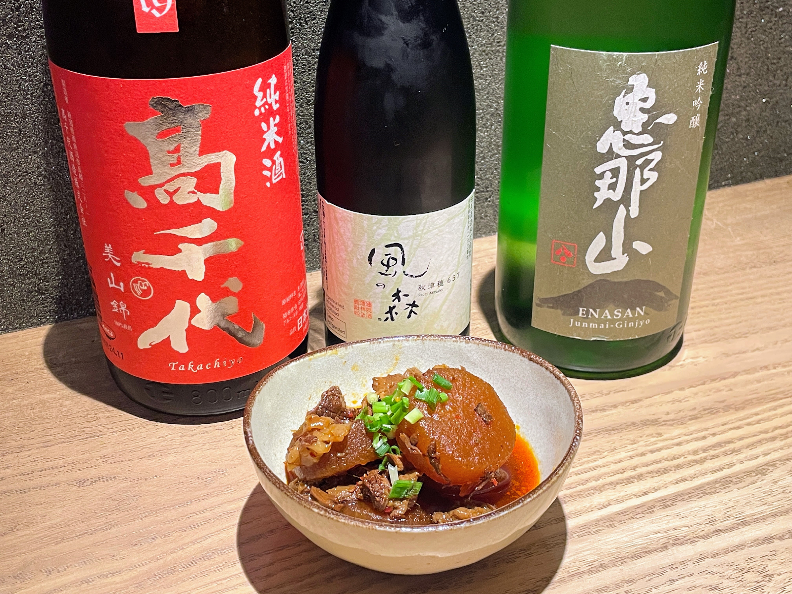 日本酒の瓶3本、惣菜が入ったお皿