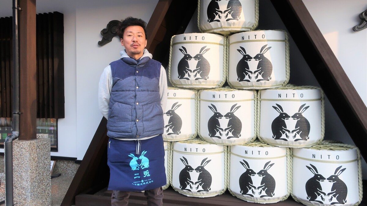 a man in front of the sake barrel