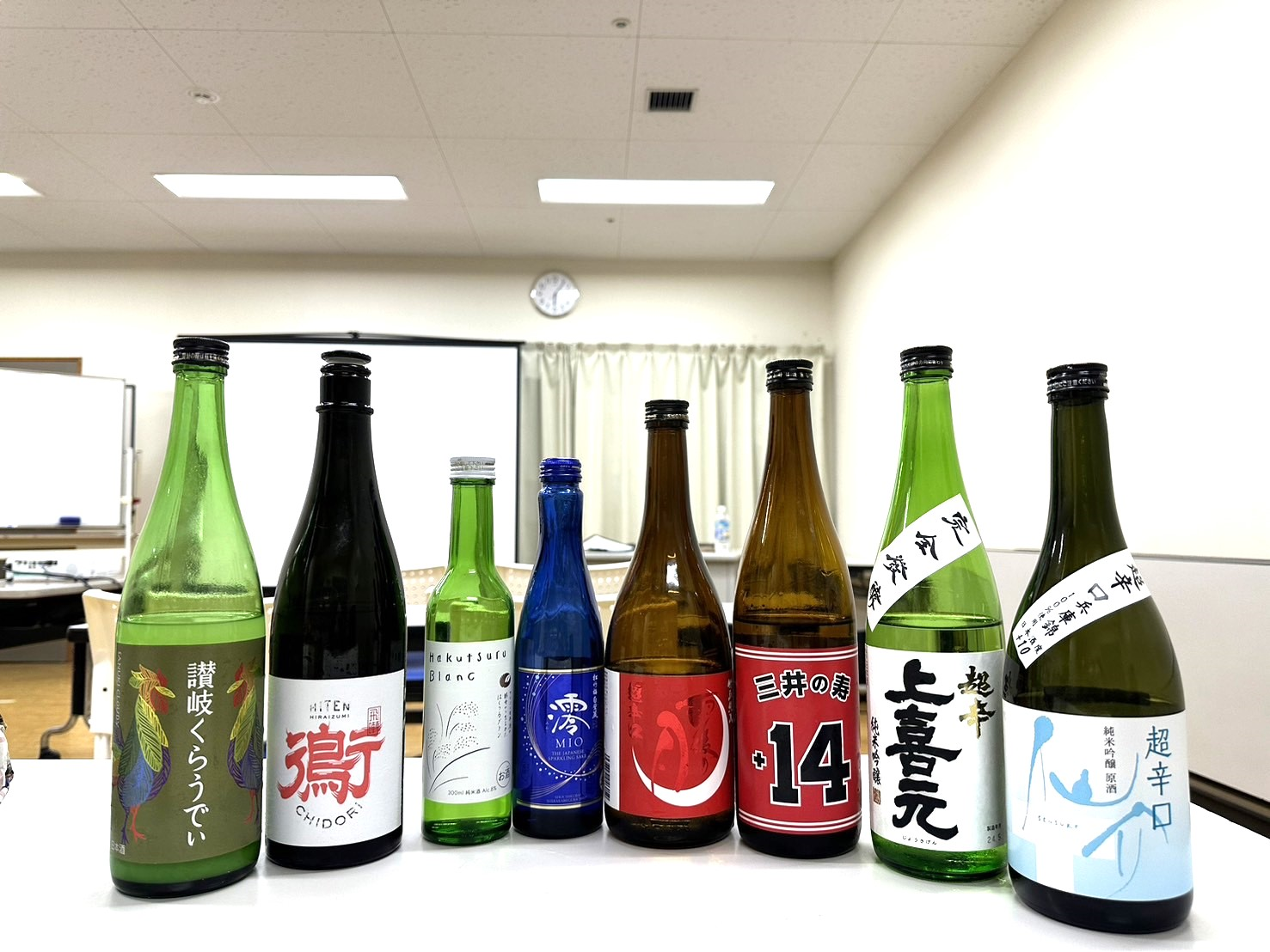 テーブルの上に日本酒の瓶がたくさん並んでいる